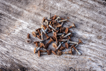 A pile of used Stainless Steel Wafer Head Self Drilling Screws covered in rust on an old wooden floor.