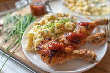 Fototapeta premium Deliciouse homemade chicken drumsticks with barbecue sauce and potato salad on a plate