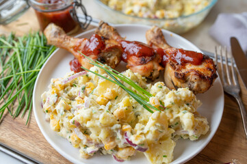 Deliciouse homemade chicken drumsticks with barbecue sauce and potato salad on a plate