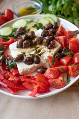 Oven baked feta cheese with marinated kalamata olives and vegetables on a plate. Delicous greek food