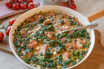 Homemade cubed salmon fillet with spinach in a creamy sauce