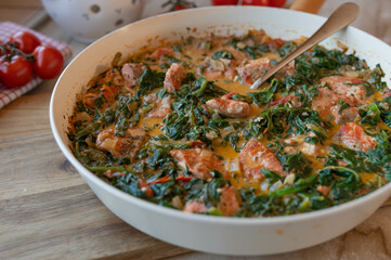 Homemade cubed salmon fillet with spinach in a creamy sauce