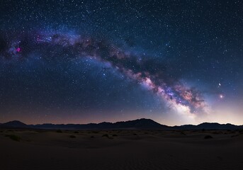 Obraz premium A breathtaking celestial river of stars arches over a tranquil desert landscape under a deeply dark night sky.