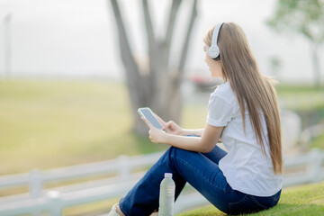 Asian women sit and listen to music in the park.
