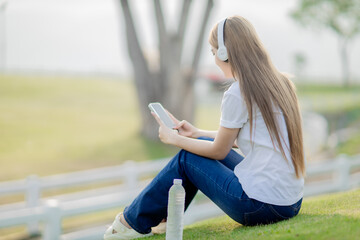 Asian women sit and listen to music in the park.