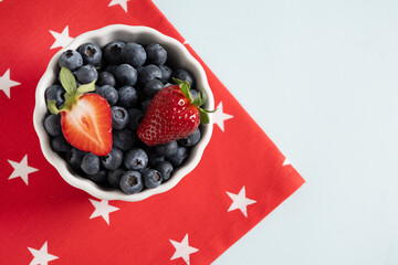 Blueberry decorated US flag in white bowl on blue background. Concept preparations for Patriotic...