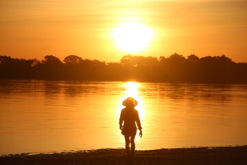 Fototapeta premium silhueta de mulher no por do sol nas margens do rio araguaia, tocantins 