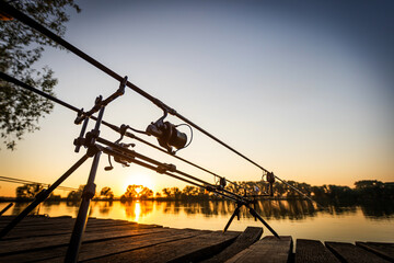 Fishing carp rods and reel on sunset background. Tools for fishing.	