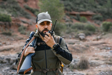 Fototapeta premium Hunter using walkie talkie while holding rifle