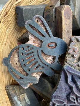 Conejo sello met&aacute;lico en hierro fundido con base de madera metido en una cesta en un mercadillo, para uso textil, pintura, decoraci&oacute;n, apliques , elementos emblem&aacute;ticos artesanos viejos, antiguos