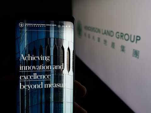 Stuttgart, Germany - 03-14-2025: Person holding web page with logo of company Henderson Land Development Co. Ltd. on screen in front of logo. Focus on center of phone display.