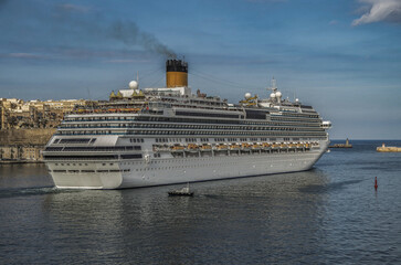 Gigantic cruiseship cruise ship liner Fascinosa docked at pier terminal in old town Valletta, Malta...