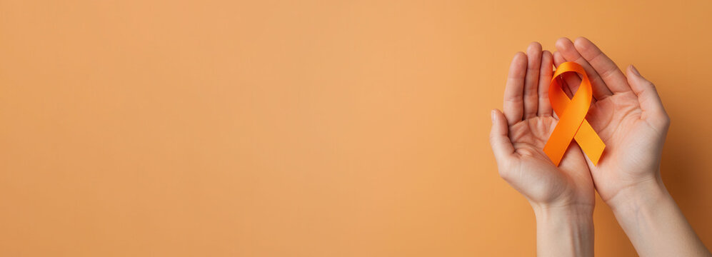 Skin cancer awareness month concept. Hands of woman holding orange color ribbon. Symbolic for Multiple Sclerosis day, self harm awareness, leukemia and kidney cancer. Flat lay, banner, copy space. - Powered by Adobe