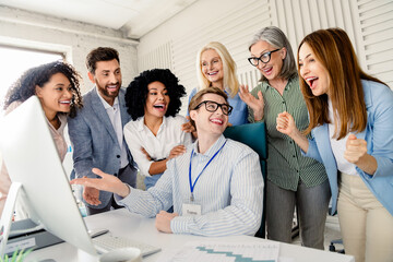 Group of diverse coworkers celebrating a successful business achievement in the office during a collaborative meeting