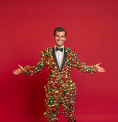 Handsome and irresistible man with a charming smile, wearing a tuxedo made of Christmas ornaments, standing in front of a solid background, in the spirit of the holidays, Christmas, and New Year
