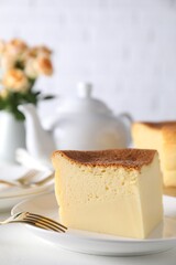 Piece of tasty Japanese Castella sponge cake and fork on white table, closeup