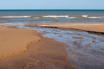 Spring runoff from higher above the beach flows casually over the beach sand to Lake Michigan in late March at Harrington Beach State Park, Belgium, Wisconsin