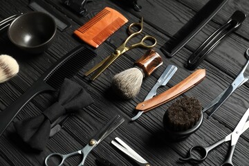 Many different barber's tools on black wooden table, above view