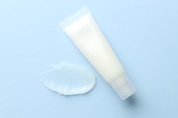 Moisturizing lip balm and tube on light blue background, top view