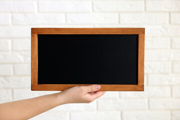 Woman holding blank small blackboard indoors, closeup