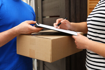 Receiver signing for delivered parcel from courier indoors, closeup