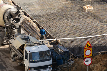 Construction site with concrete mixer and worker at building location