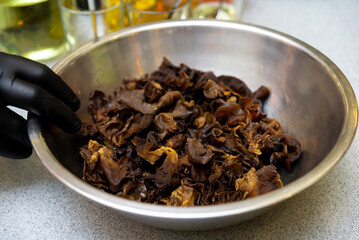 Soaked black fungus mushrooms in metal bowl. Close-up of rehydrated black fungus mushrooms in a...