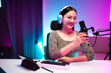 Teenager girl hosts podcast in her room using LED lights, computer, headphones, condenser...