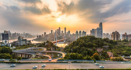 Aerial view of Chongqing city skyline at sunset with Yuzhong district buildings and Yangtze river. Urban landscape and transportation background.
