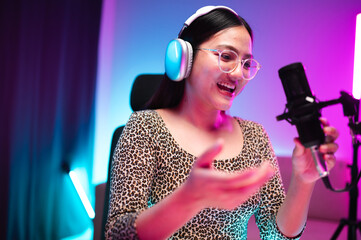 Teenager girl hosts podcast in her room using LED lights, computer, headphones, condenser...