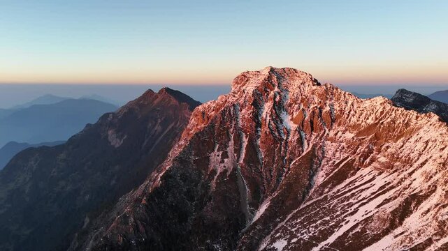 The snowy white Yushan Main Peak fills the screen. Far away, you can see Yushan North Peak. It's evening time, and sunlight is shining on the snow-covered main peak, making it glow beautifully against - Powered by Adobe