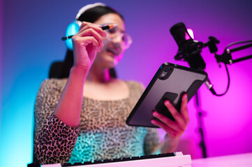 Teenager girl hosts podcast in her room using LED lights, computer, headphones, condenser...