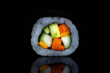 Close up of a colorful vegan sushi roll with avocado, cucumber, and carrots, reflecting on a black background