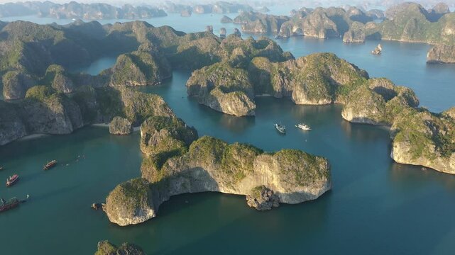 Top view of green vegetated karst islands and several boats sailing in Lan Ha Bay, near Cat Ba island, Vietnam