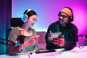 Teenagers, men and women, host podcasts in a room using LED lights, computers, headphones,...