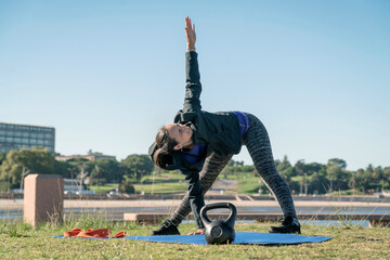 Fit woman stretching on a mat outdoors by the sea.