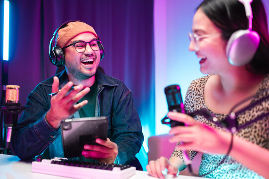 Teenagers, men and women, host podcasts in a room using LED lights, computers, headphones, condenser microphones, and tablets to share their knowledge and experiences through live online broadcasts. - Powered by Adobe