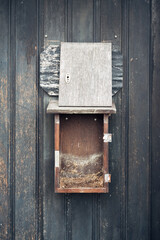 A wooden box with a hole in the front is hanging on a wall