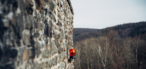 A red and yellow fire alarm sits on a stone wall