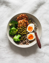 Balanced lunch - buckwheat, broccoli, chopped chicken cutlets, boiled egg on a light background, top view