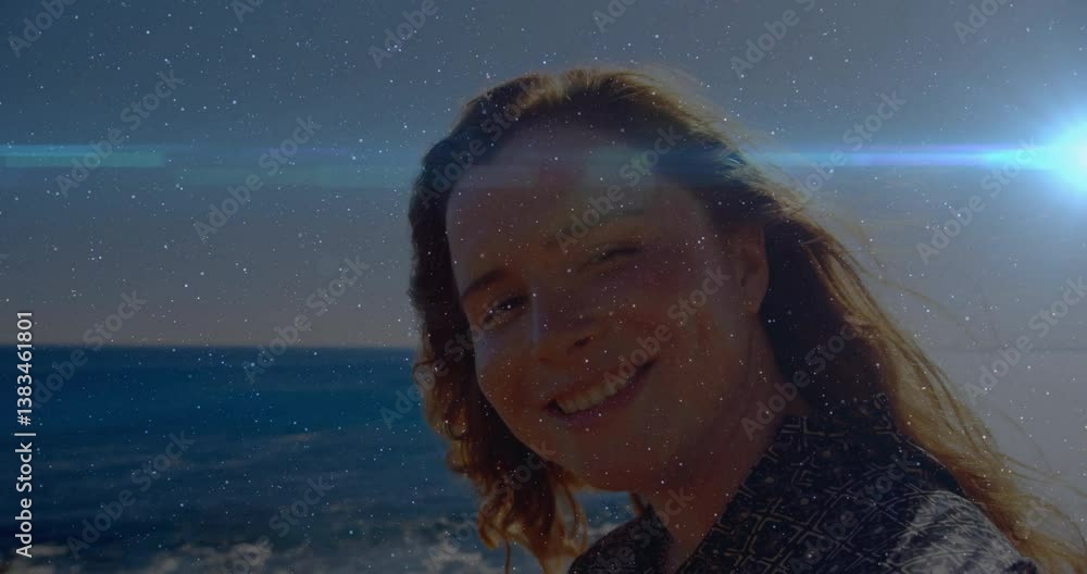 Poster animation of person smiling by ocean with sparkling light effects in background