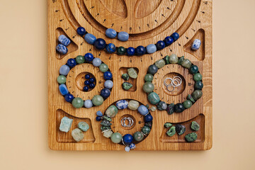 Jewelry-making board with natural stone bracelets. Assorted gemstone bracelets and raw crystals for crafting. Handmade stone bead bracelets.