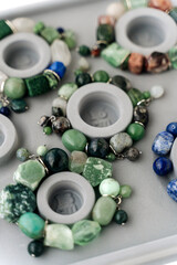 Jewelry-making board with natural stone bracelets. Assorted gemstone bracelets and raw crystals for crafting. Handmade stone bead bracelets.