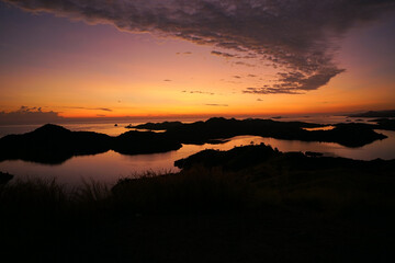 Obraz premium Breathtaking sunset over Riung Islands, Indonesia. The golden sky reflects on the calm sea, silhouetting the scattered islets. A perfect tropical paradise with stunning natural beauty and serene vibes