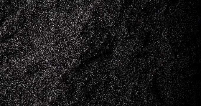 Dark crumpled texture in slow spin. Rough black surface rotates smoothly with gritty depth in gentle motion. Ideal for abstract ads in 4K.