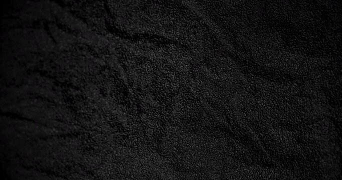 Rough black surface rotates smoothly with gritty depth in gentle motion. 