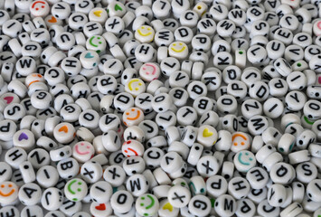 A background of beads with letters and emoticons, a basic piece for craftwork.