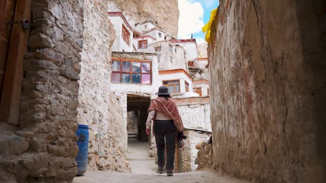 Indian tourist girl exploring old built structure of Phugtal Monastery in Zanskar, Ladakh, India. Ancient Buddhist monastery made in cave. Travel and holidays concept. 