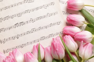 Beautiful tulips on sheets with music notes, top view
