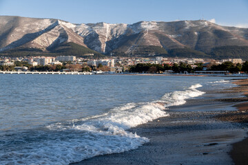 A beautiful mountain range with a city in the background. The city is full of buildings and the water is calm